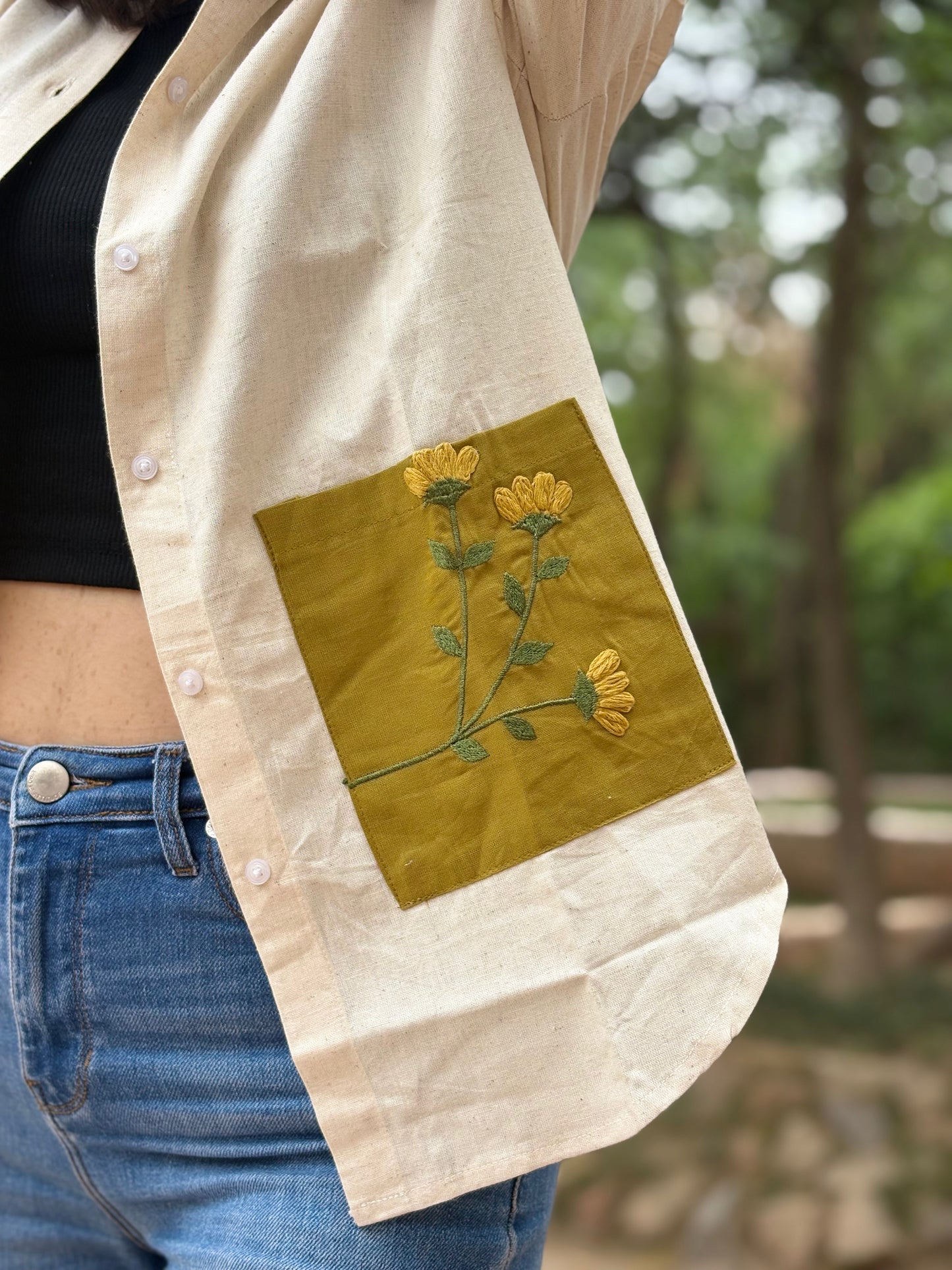 Beige jacket with floral embroidery on a blurred natural background
